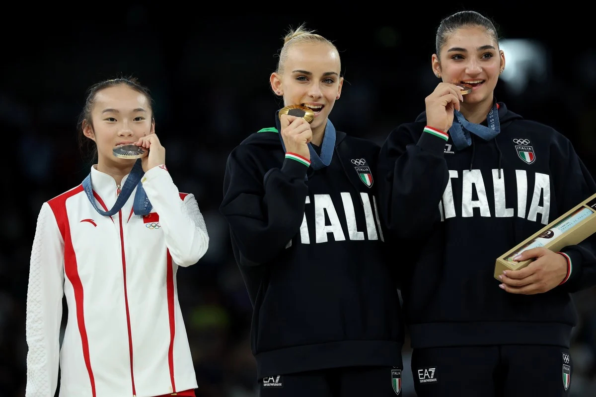 Chinese Gymnast Zhou Yaqin biting her medal alognisde two Italian medal winners at Paris 2024 Olympics.