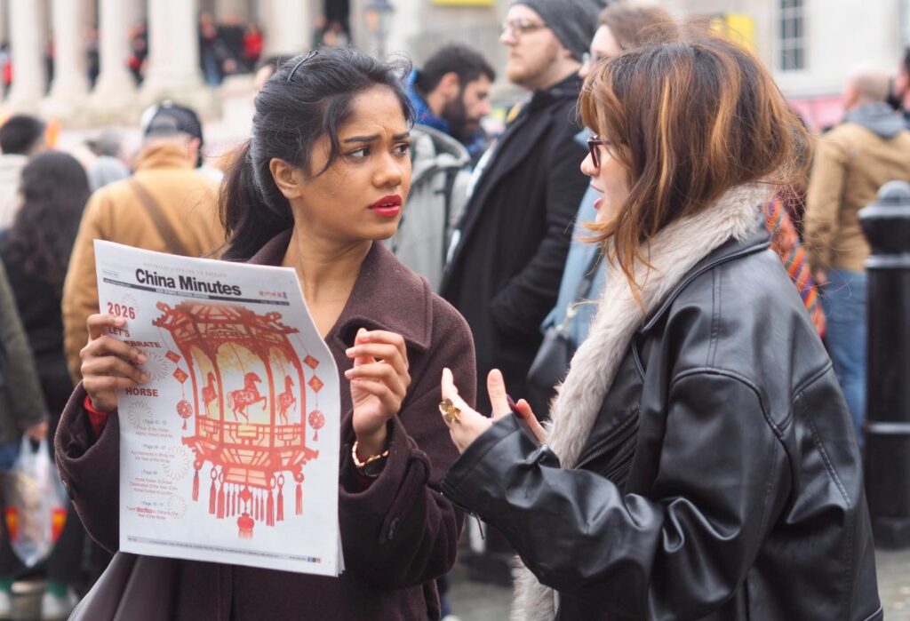 Two attendees reading the China Minutes Chinese New Year newspaper.